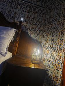 una lámpara sentada en una mesa junto a una cama en Dar Lalla Kenza, en Fez
