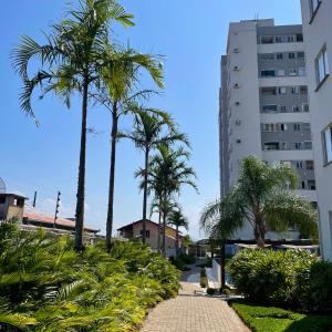 um passadiço com palmeiras e um edifício em O seu apê na praia, 2 dormitórios, com piscina em Barra Velha