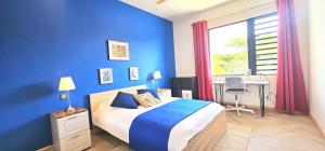 a blue bedroom with a bed and a desk and a window at Golf View Villa in Roches Noires