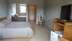 um quarto com uma cama, uma televisão e uma mesa em Hotel Dominguez Master em Nova Friburgo