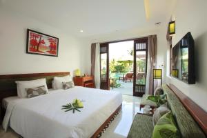 a bedroom with a large white bed and a patio at Green Boutique Villa in Hoi An