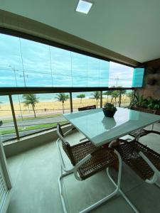 ヴィラ・ヴェーリャにあるApartamento De frente ao mar, linda varanda com churrasqueiraの大きな窓のある部屋にあるテーブルと椅子