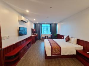 a bedroom with a bed and a desk and a television at glory 3 hotel 北宁格洛瑞3好酒店 in Bồ Sơn