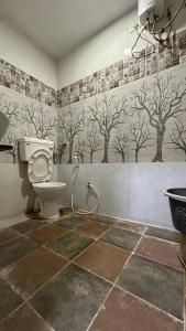 a bathroom with a toilet and trees on the wall at Hotel New Shiv Kunj in Vadodara