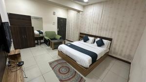 ein Schlafzimmer mit einem Bett und einem Stuhl in einem Zimmer in der Unterkunft Hotel New Shiv Kunj in Vadodara