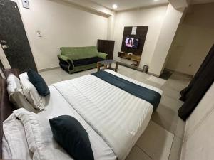 a bedroom with a bed and a chair and a television at Hotel New Shiv Kunj in Vadodara