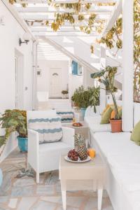 una sala de estar con muebles blancos y plantas en Dibellee Mykonos boutique studios, en Glastros