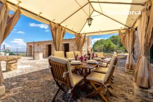 een houten tafel en stoelen onder een tent bij Cases de Son Roig by Rentallorca in Sant Joan