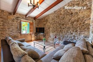 een woonkamer met een bank en een stenen muur bij Cases de Son Roig by Rentallorca in Sant Joan