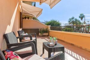 a patio with chairs and tables on a balcony at Apartamento NICE4YOU by Rentallorca in Port d'Alcudia