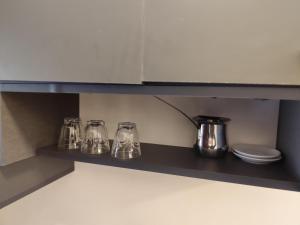 a kitchen shelf with four glass items on it at Gentle Breeze Studio 1 in Amman