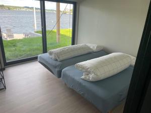 two pillows on a bed with a view of the water at Unikt feriested med stor privat brygge in Bamble