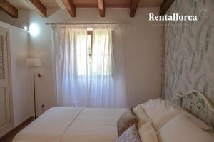 1 dormitorio con cama blanca y ventana en Finca Ca'n Sec by Rentallorca, en Sóller