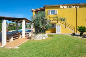 a villa with a swimming pool and a yellow house at Cristi Bressals by Rentallorca in Alcudia