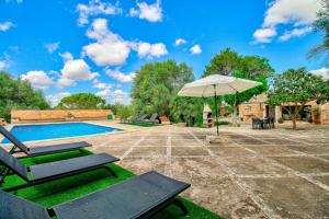 patio z parasolem i krzesłami oraz basenem w obiekcie Finca Can Garbeta by Rentallorca w Manacorze