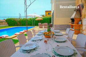 Can Bombarda by Rentallorca في يوبي: طاولة مع أطباق وكؤوس النبيذ يجلس على الفناء