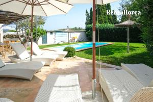 a group of white chairs and umbrellas next to a pool at Finca es Collet by Rentallorca in Manacor
