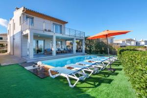 una piscina con tumbonas y una sombrilla junto a una casa en Villa Ca'n Tugores by Rentallorca, en Colonia de San Pedro