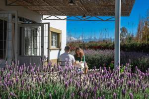 a man and woman sitting at a table in a garden with purple flowers at Boutique Vineyard and Wine Lodge in Maipú