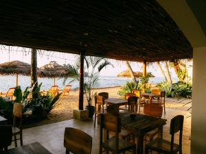 ein Restaurant am Strand mit Tischen und Stühlen in der Unterkunft Blue Waves Surf Hotel Sri Lanka in Ahangama