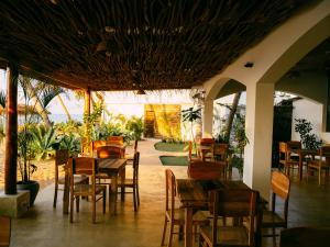 ein Restaurant mit Tischen und Stühlen und eine Terrasse in der Unterkunft Blue Waves Surf Hotel Sri Lanka in Ahangama