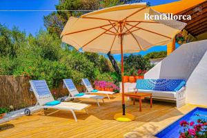 eine Gruppe Stühle und ein Sonnenschirm neben einem Pool in der Unterkunft Cas Predi by Rentallorca in Can Picafort