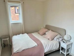 Un dormitorio con una cama con almohadas rosas y una ventana en Pass the Keys Cosy One Bedroom House with Parking, en Borehamwood