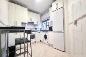 a kitchen with white cabinets and a washer and dryer at Apartamento Saavedra in Posada de Llanes