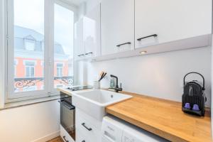 biała kuchnia ze zlewem i oknem w obiekcie Lille Centre apartment with character w Lille