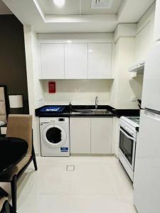 a white kitchen with a sink and a dishwasher at Charming city apartment in Dubai