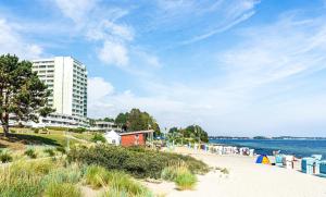einen Strand mit einem hohen weißen Gebäude und dem Meer in der Unterkunft Ferienpark Sierksdorf App 452 - Strandlage in Sierksdorf