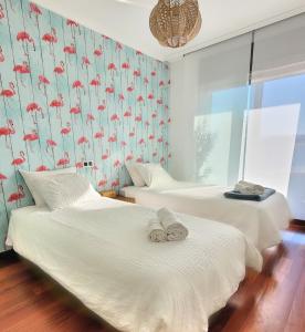 2 camas en una habitación con papel pintado de flamencos rojos en Apartamento Ensenada da Lanzada, en Rouxique