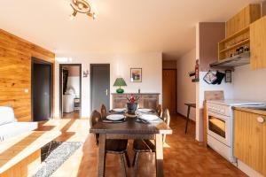 a kitchen and living room with a table and chairs at Le petit Schuss - A 10min des remontées mécaniques in La Giettaz