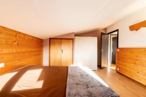 um quarto com uma cama grande e paredes de madeira em Le petit Schuss - A 10min des remontées mécaniques em La Giettaz