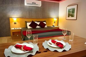 1 dormitorio con 1 cama y mesa de madera con platos y copas de vino en Lohaip Residences Med Barra, en Río de Janeiro
