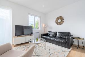 a living room with a black leather couch and a tv at Marcq en Baroeul appartement deux chambres in Marcq-en-Baroeul