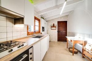 een keuken met witte kasten, een wastafel en een tafel bij Finca Es Coste by Rentallorca in Pollença