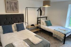 a bedroom with two beds and a bench in it at Forest Loft by Afan Valley Escapes in Port Talbot