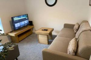 a living room with a couch and a flat screen tv at Forest Loft by Afan Valley Escapes in Port Talbot
