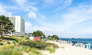 a beach with a tall white building and the ocean at Ferienpark Sierksdorf App 382 - Strandlage in Sierksdorf