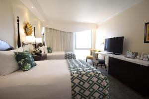 um quarto de hotel com uma cama grande e uma secretária em Courtleigh Hotel & Suites em Kingston