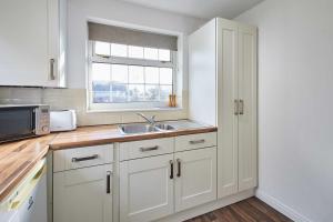 a kitchen with white cabinets and a sink and a window at Host & Stay - Spring Gardens in Cayton