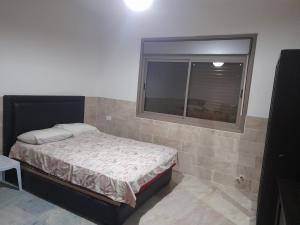 a small bedroom with a bed and a window at Wild strawberry Farm Ajloun مزرعة القيقب عجلون in Ishtafaynā