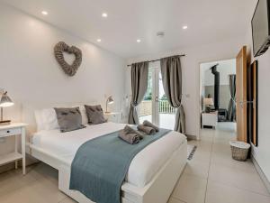 a white bedroom with a large bed with a heart hung on the wall at 2 Bed in Totnes 93062 in Marldon