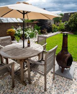 a table with an umbrella and two chairs and a bottle of beer at Linburn Cottage Dunfermline near Edinburgh in Dunfermline