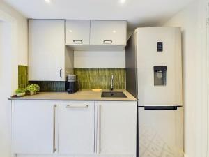 una cocina con armarios blancos y fregadero en Be London - Notting Hill Apartments, en Londres