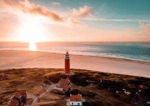 a lighthouse on the shore of a beach with the ocean at Puur Texels 9a in De Koog +12 photos