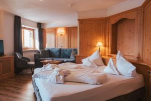 ein Hotelzimmer mit einem Bett und einem Sofa in der Unterkunft Parkhotel Holzerhof in Meransen