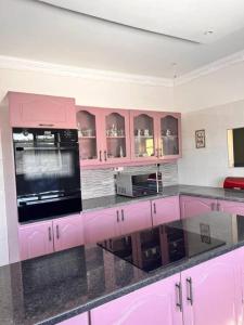 cocina con armarios rosas y encimera en immaculate 5 bedroomed house en Bulawayo