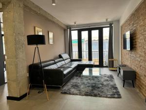 sala de estar con sofá de cuero negro y pared de ladrillo en Elegante piso reformado a 1km del centro en Granada